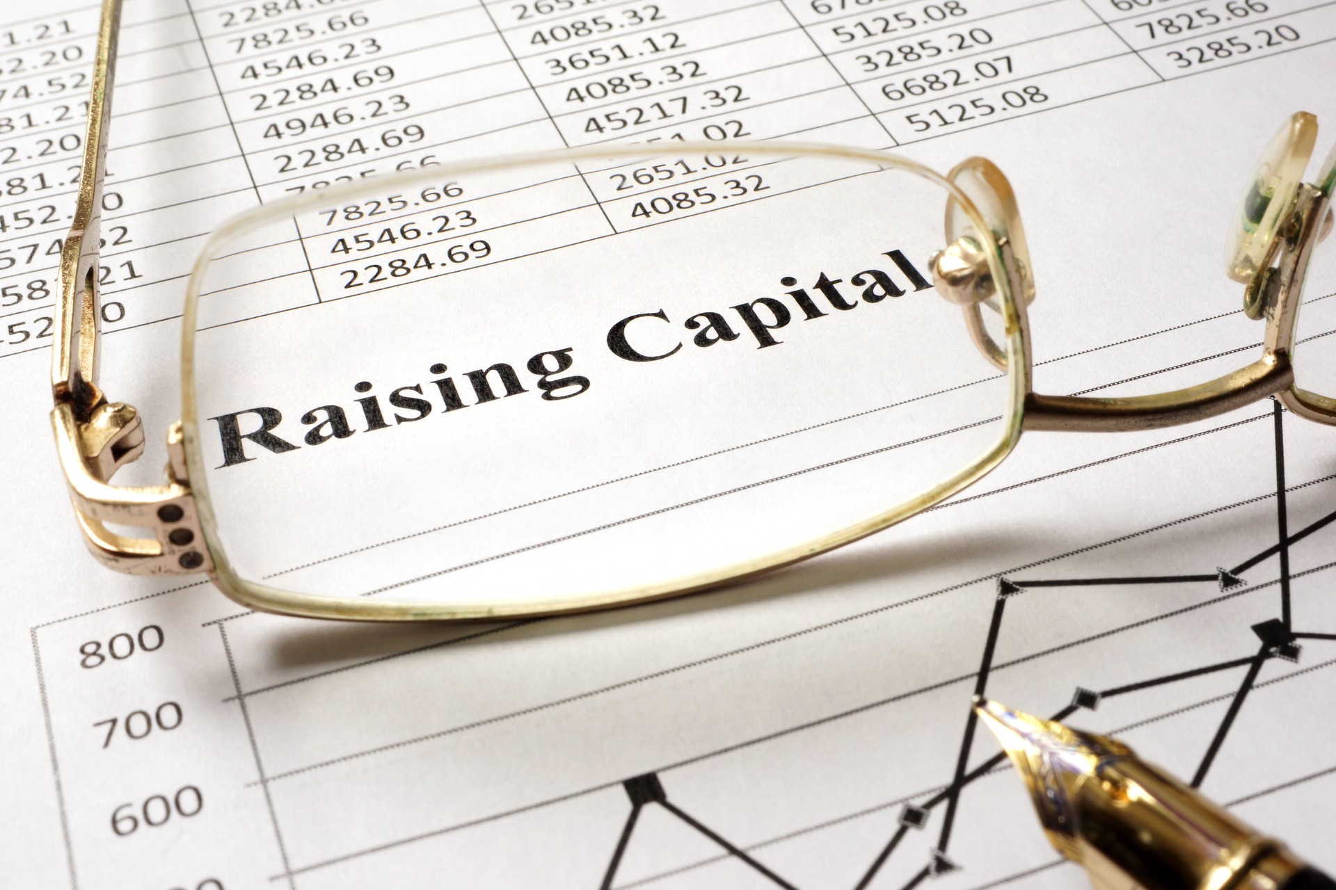 Sign raising capital on a paper and glasses.